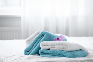 Photo of Clean towels and pink orchid on bed