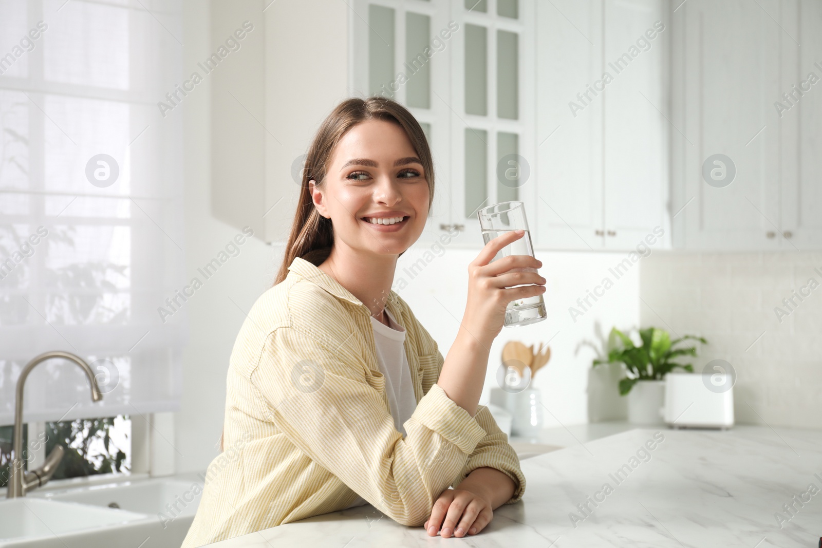 Photo of Woman with glass of tap water in kitchen