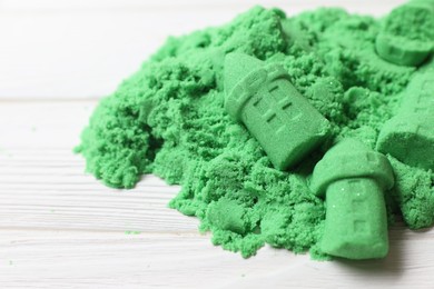 Photo of Castle figures made of green kinetic sand on white table, closeup