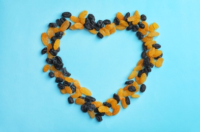 Photo of Frame made of raisins on color background, top view with space for text. Dried fruit as healthy snack