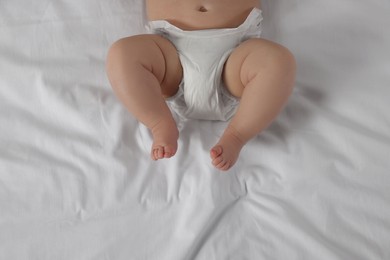 Photo of Little baby in diaper lying on bed, top view
