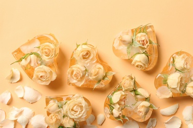 Heart shaped ice cubes with roses on color background, flat lay composition