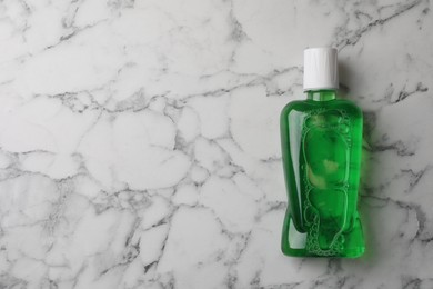 Fresh mouthwash in bottle on white marble table, top view. Space for text