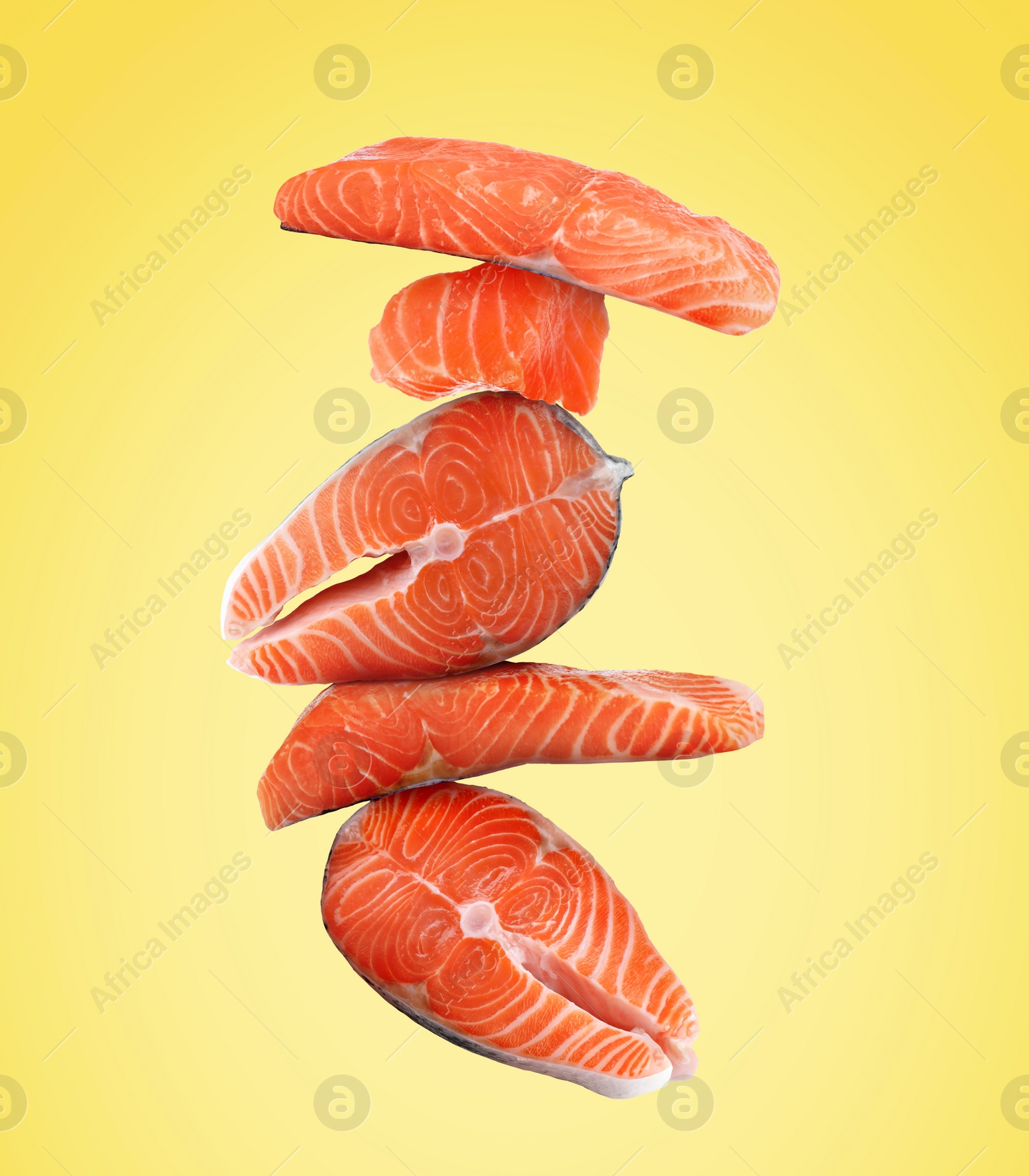 Image of Cut fresh salmon falling on yellow background