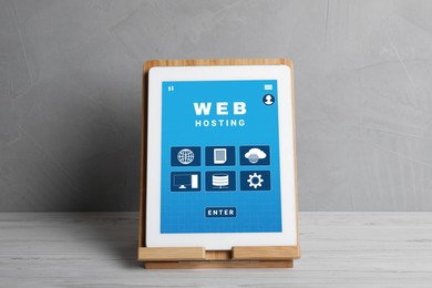Image of Web hosting service. Modern tablet on white wooden table