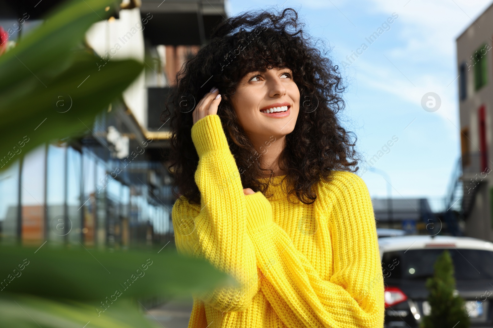 Photo of Happy young woman in stylish yellow sweater outdoors