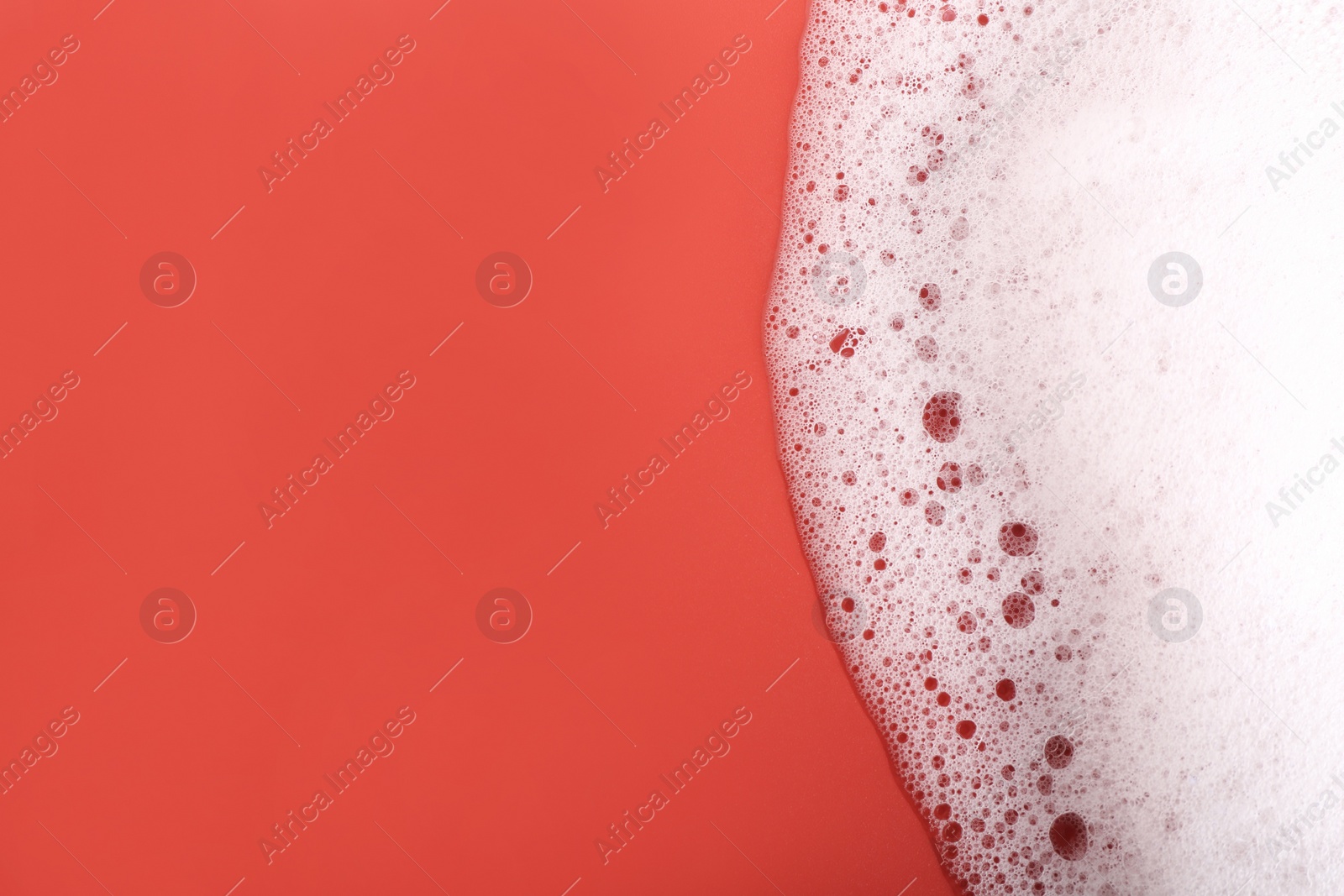 Photo of White foam with bubbles on red background, top view. Space for text