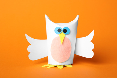 Toy owl made of toilet paper hub on orange background