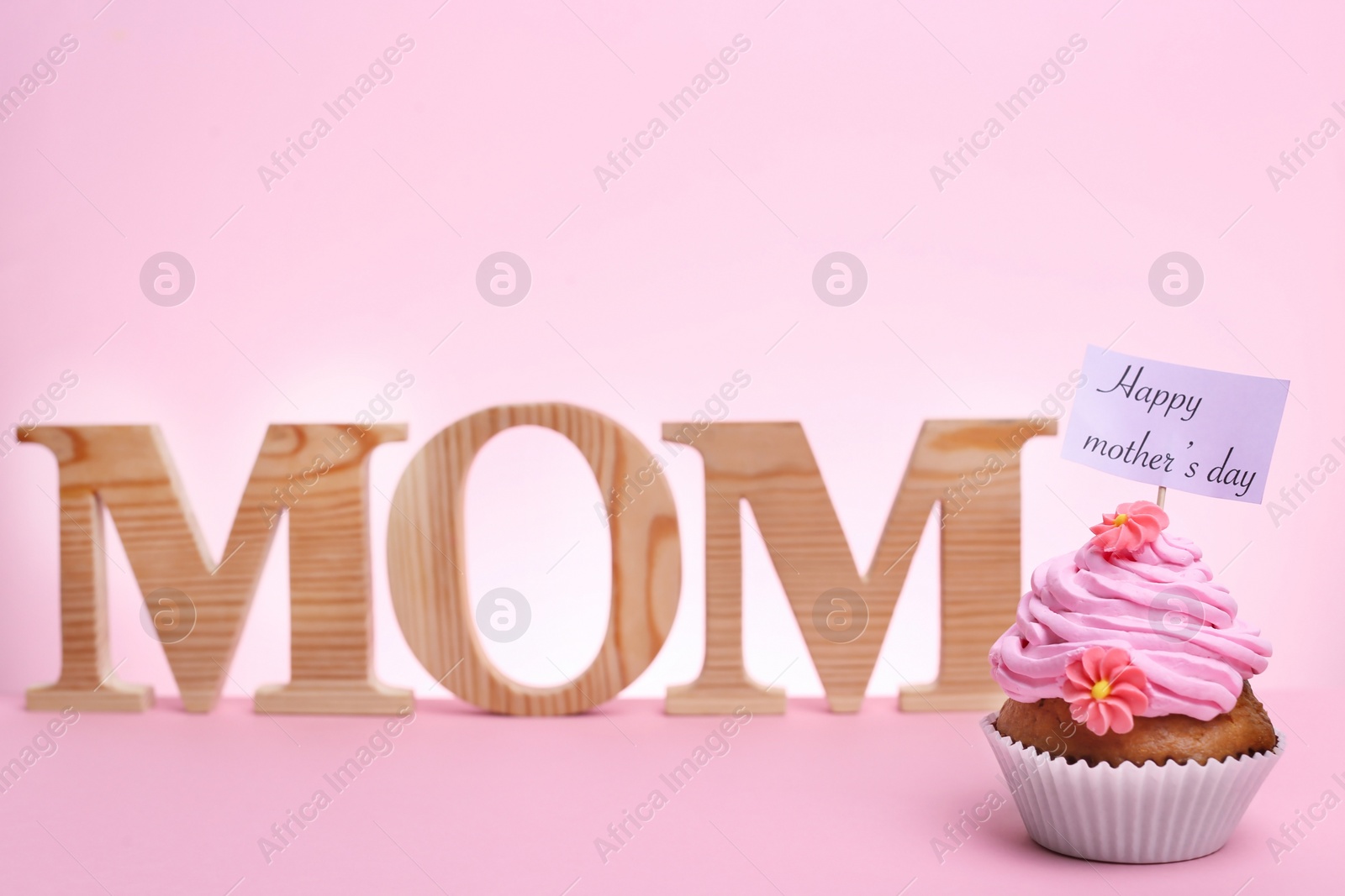 Photo of Tasty cupcake for Mother's Day and word MOM on color background