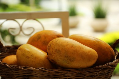 Photo of Basket with delicious ripe yellow mangos outdoors, closeup