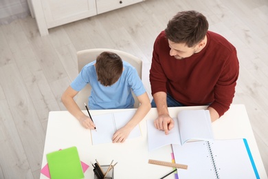 Photo of Dad helping his son with homework in room, above view