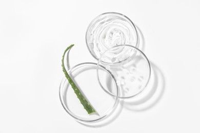 Photo of Petri dishes with aloe plant and cosmetic products on white background, top view
