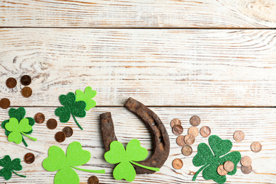 Photo of Flat lay composition with horseshoe on white wooden background, space for text. St. Patrick's Day celebration