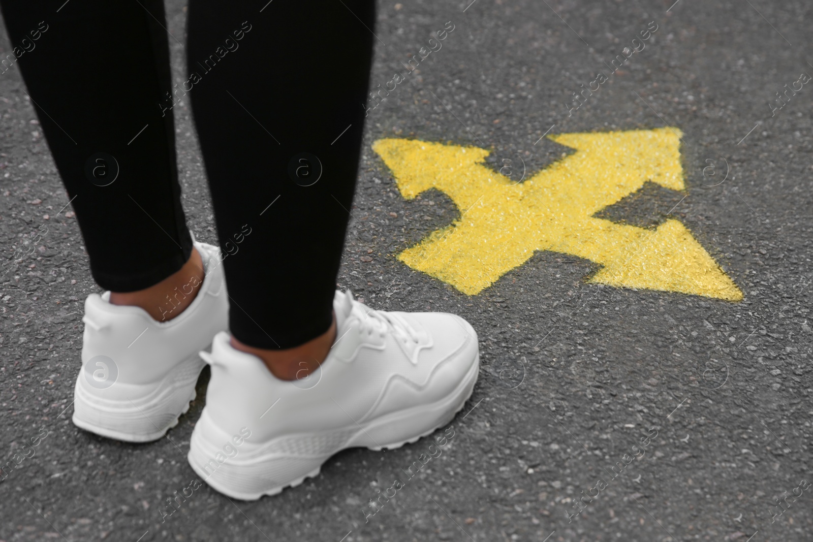 Photo of Woman standing near arrow on asphalt, closeup