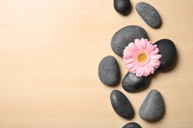 Photo of Spa stones with flower on wooden background, top view. Space for text