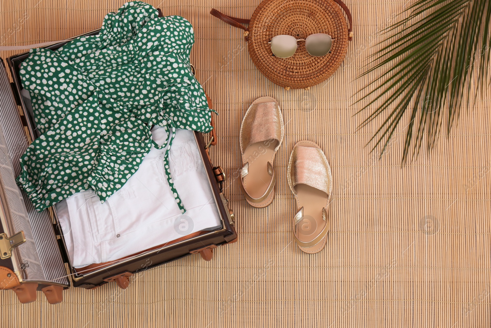 Photo of Flat lay composition with open suitcase on bamboo mat