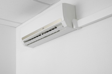 Photo of Modern air conditioner on white wall indoors