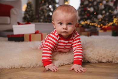 Photo of Cute baby in bright Christmas pajamas on floor at home