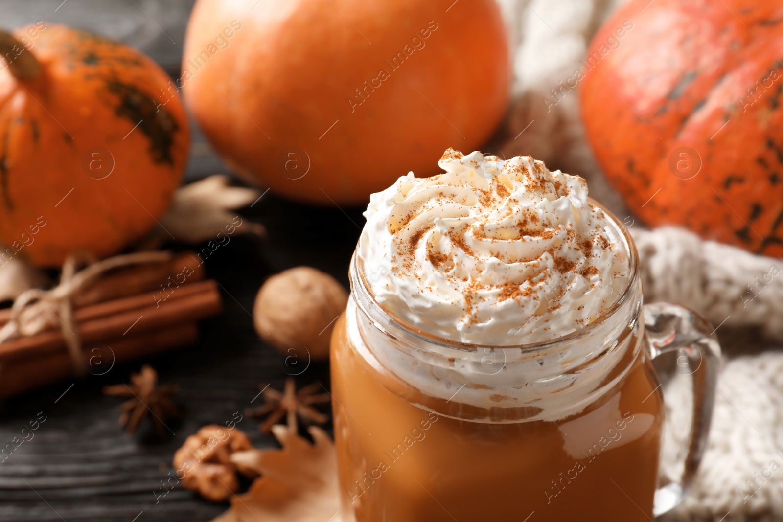 Photo of Mason jar with tasty pumpkin spice latte on table, closeup