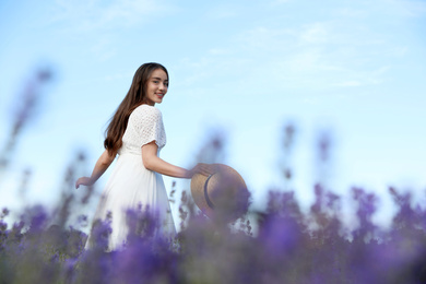 Photo of Young woman with straw hat in lavender field on summer day