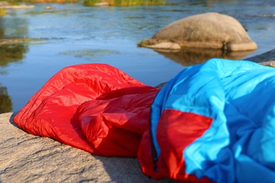 Bright sleeping bag near lake on sunny day