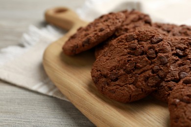 Delicious chocolate chip cookies on light wooden table, closeup