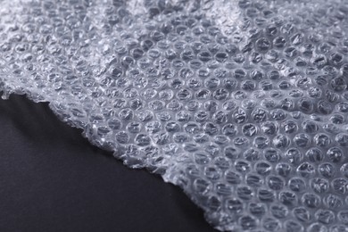 Photo of Transparent bubble wrap on black background, closeup. Space for text