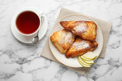 Photo of Fresh tasty puff pastry with sugar powder, pear and aromatic tea served on white marble table, flat lay
