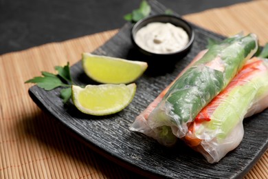 Delicious rolls wrapped in rice paper served on black table, closeup