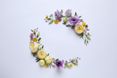 Wreath made of beautiful flowers and green leaves on light background, flat lay. Space for text