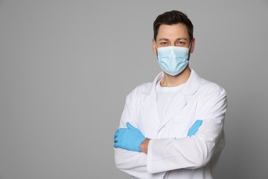 Photo of Doctor or medical assistant (male nurse) in uniform with protective mask on light grey background. Space for text