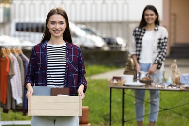 Women organize garage sale with different items in yard