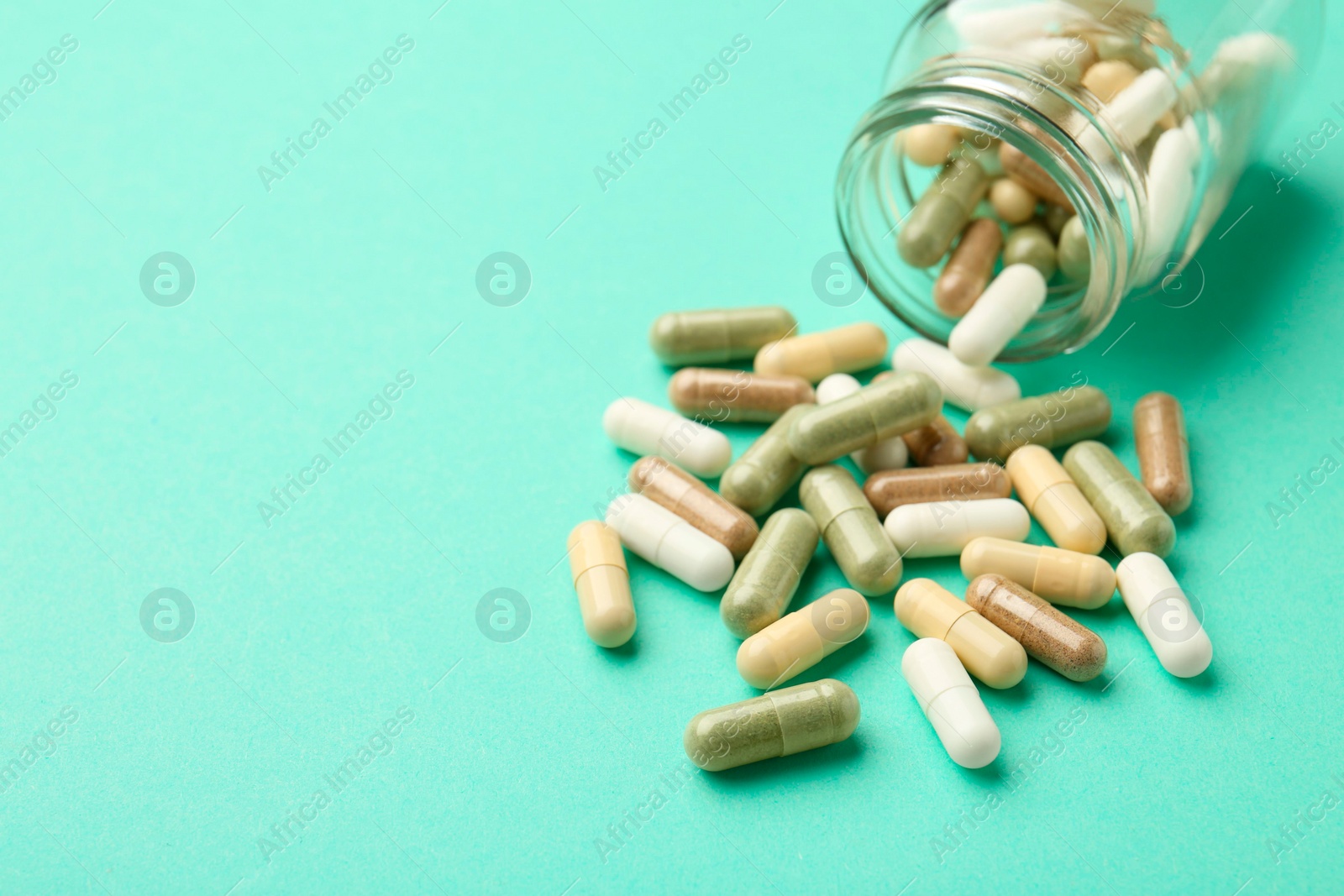 Photo of Vitamin pills and bottle on mint color background. Space for text