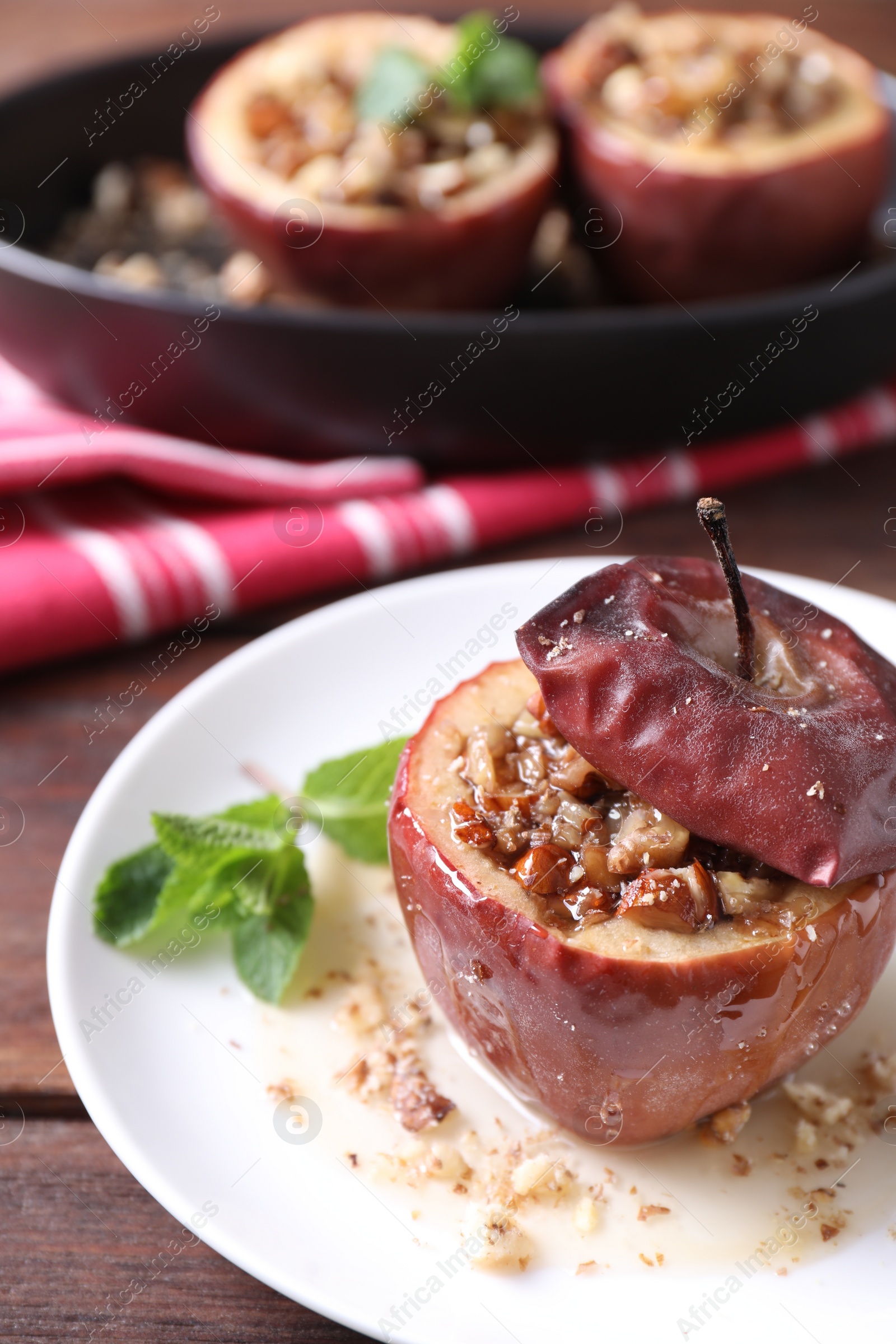 Photo of Tasty baked apple with nuts, honey and mint on wooden table, closeup