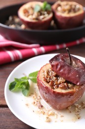 Photo of Tasty baked apple with nuts, honey and mint on wooden table, closeup