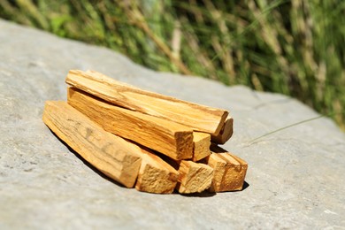 Photo of Many palo santo sticks on stone outdoors, closeup