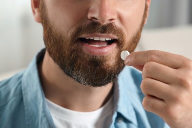 Photo of Man taking pill on blurred background, closeup view