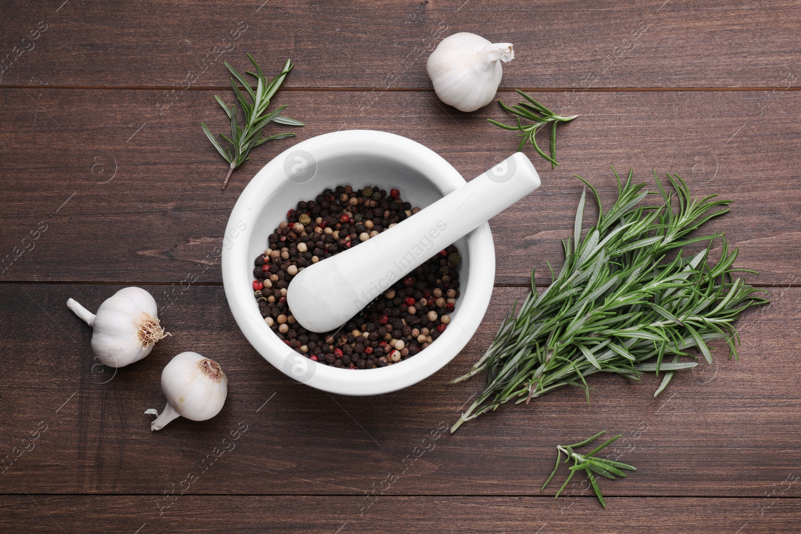 Photo of Fresh rosemary, mortar and garlic on wooden table, flat lay