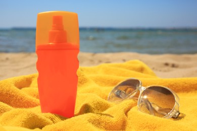 Sunscreen, sunglasses and towel on sandy beach. Sun protection care