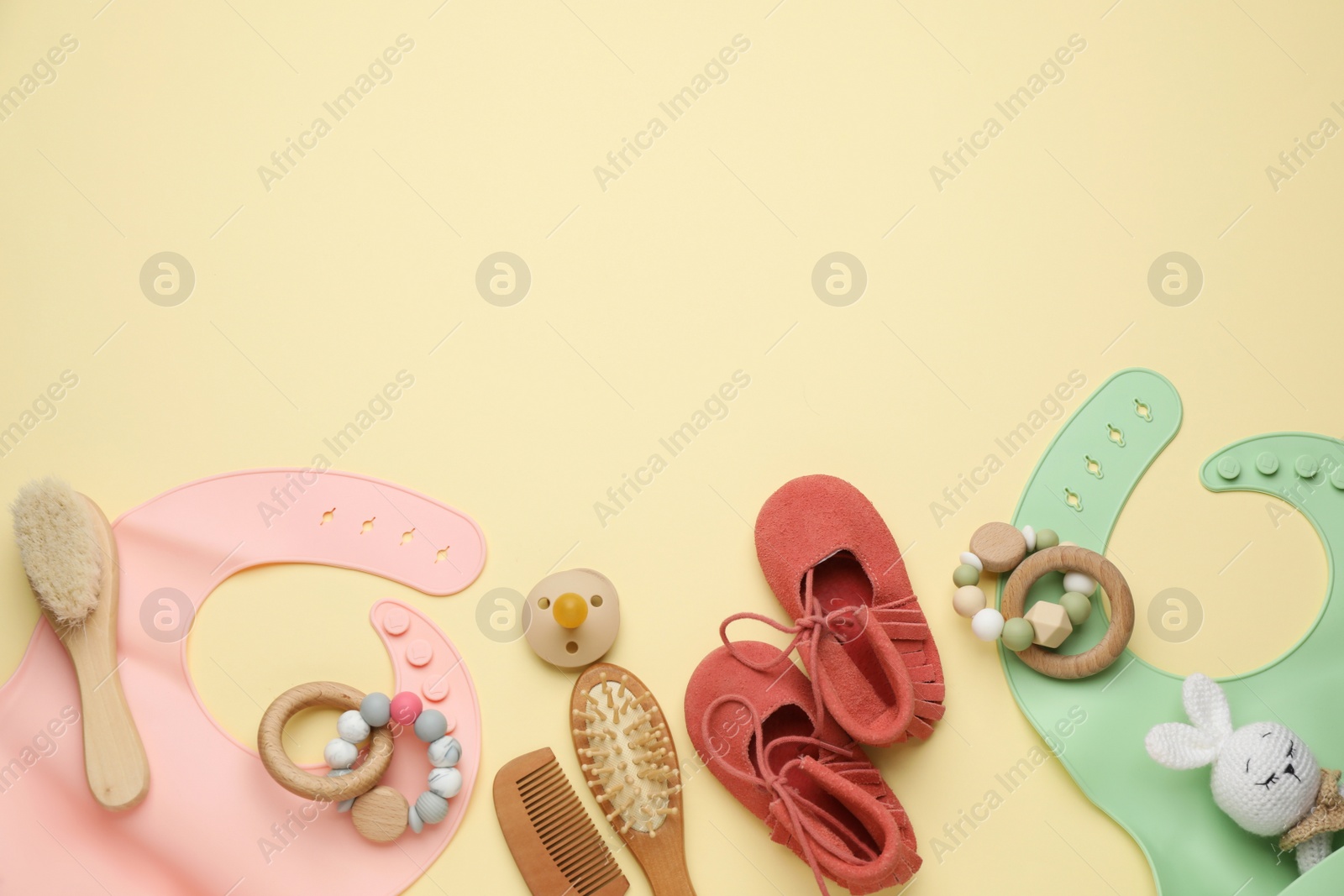 Photo of Flat lay composition with baby accessories and bibs on yellow background, space for text