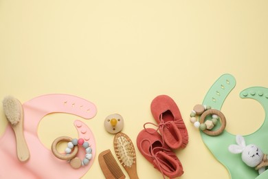 Photo of Flat lay composition with baby accessories and bibs on yellow background, space for text