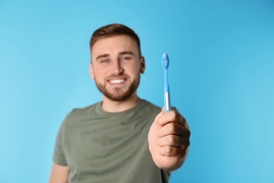Photo of Young man with brush and toothpaste on color background, space for text. Teeth care