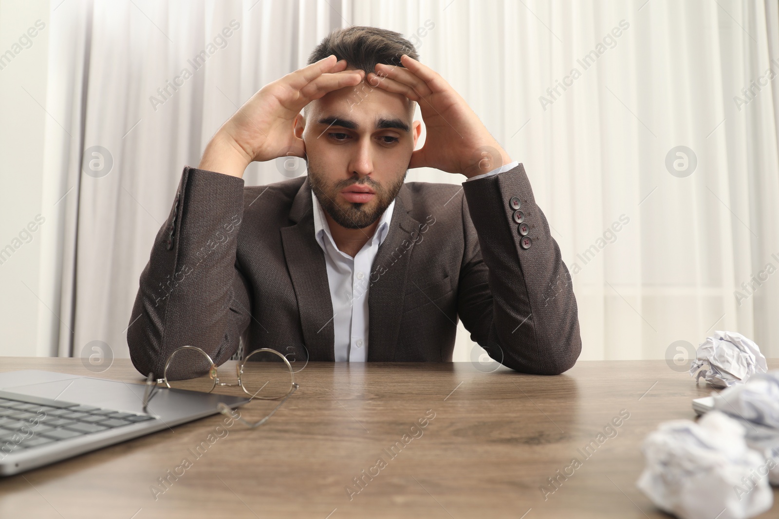 Photo of Tired sad businessman sitting at table in office, low angle view