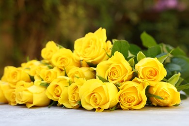 Beautiful bouquet of yellow roses on light table outdoors