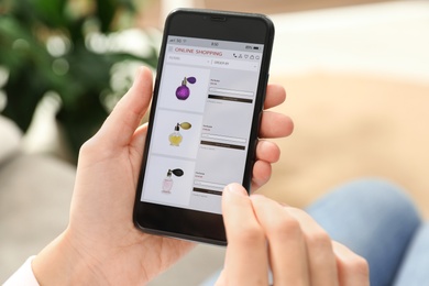 Woman using smartphone for online shopping indoors, closeup