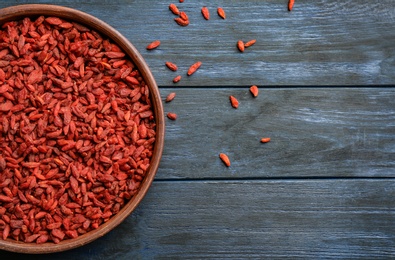 Photo of Bowl of dried goji berries on wooden table, top view with space for text. Healthy superfood