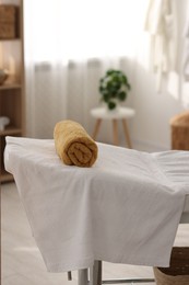 Rolled towel on massage table in spa center