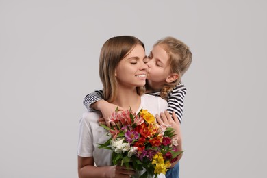 Little daughter congratulating her mom with flowers on white background. Happy Mother's Day