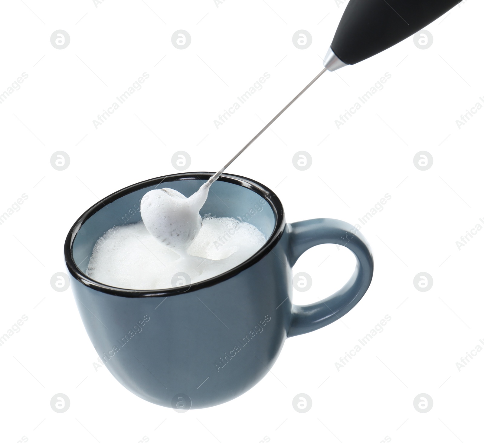 Photo of Whisking milk in cup with mini mixer (frother wand) isolated on white, closeup