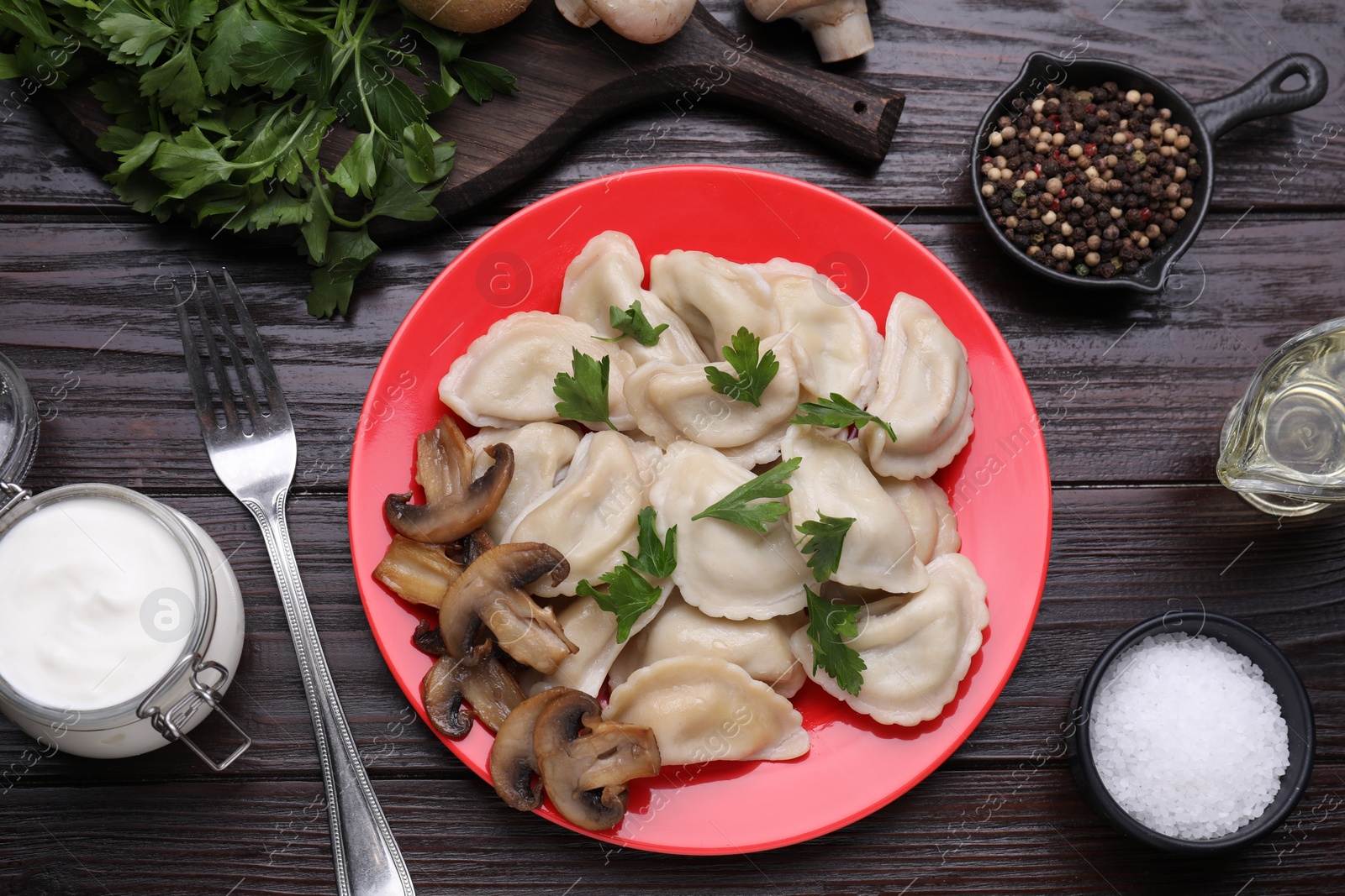 Photo of Delicious dumplings (varenyky) with potatoes, mushrooms and parsley served on brown wooden table, flat lay